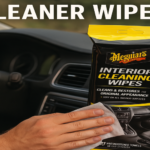 A person using the best meguiars interior cleaner for cars , wiping a dashboard with Meguiar's cleaning wipes for a spotless, refreshed look.