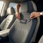 A person demonstrating how to use car seat cover by properly securing it over the seat for a snug and tailored fit inside a modern vehicle.