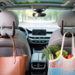 Amooca Car Seat Headrest Hooks holding a handbag and grocery bag inside a modern car for better organization.