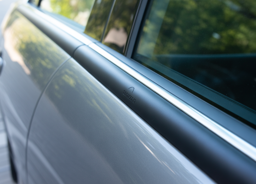 Close-up view of a sleek car door fitted with a protective Car Door Edge Guard, showing a smooth black trim along the window edge.