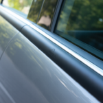 Close-up view of a sleek car door fitted with a protective Car Door Edge Guard, showing a smooth black trim along the window edge.