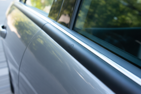 Close-up view of a sleek car door fitted with a protective Car Door Edge Guard, showing a smooth black trim along the window edge.