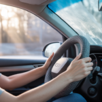 Driver using a portable heated steering wheel cover for winter to keep hands warm while driving in cold weather